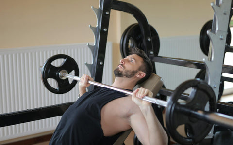 man-in-black-tank-top-holding-black-barbell-in-room